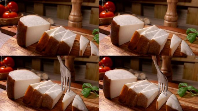 叉子的特写镜头将一块半硬的绵羊奶酪切成小块