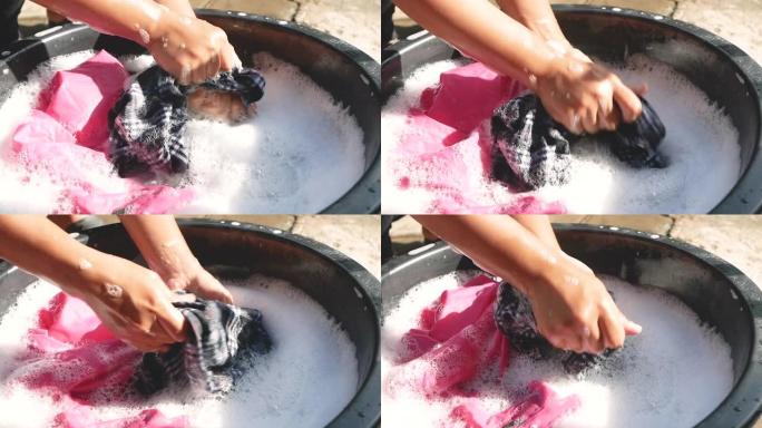 妇女用搪瓷器皿中的洗涤剂手工洗衣服。家务工作和卫生概念。