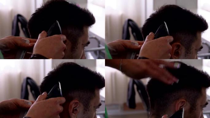 美发师正在为男性黑发客户进行男性机器理发