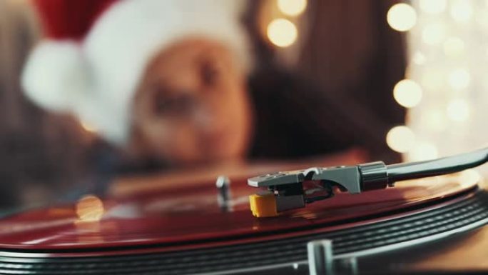 圣诞节。转盘。乙烯基唱机。戴着圣诞红帽子的模糊女人，听黑胶唱片，唱圣诞旋律黑景。诺埃尔。70年代、8