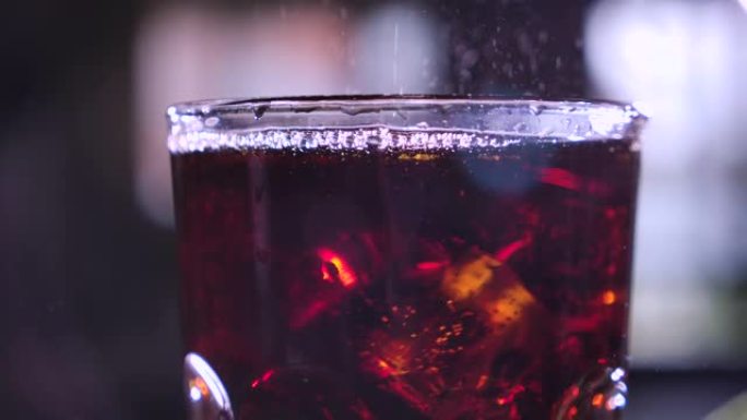 玻璃里有气泡的可乐。冰块掉进杯子里。鸡尾酒配威士忌和朗姆酒。冰镇饮料。喝碳酸汽水。口渴饮料。特写。宏