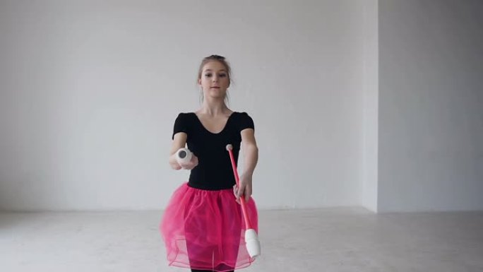 女孩体操运动员旋转苹果电脑。女孩体操运动员穿着黑色的身体和粉红色的裙子，手里拿着马卡在白色背景下围绕