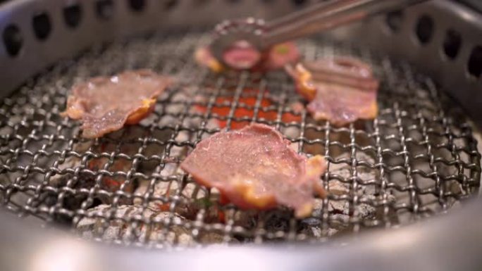 4k日式银金属铜翻转牛肉烧烤切片在烧烤架上，做得很好，中等稀有肉，煤火，日本餐厅，火焰烧烤，白盘，主