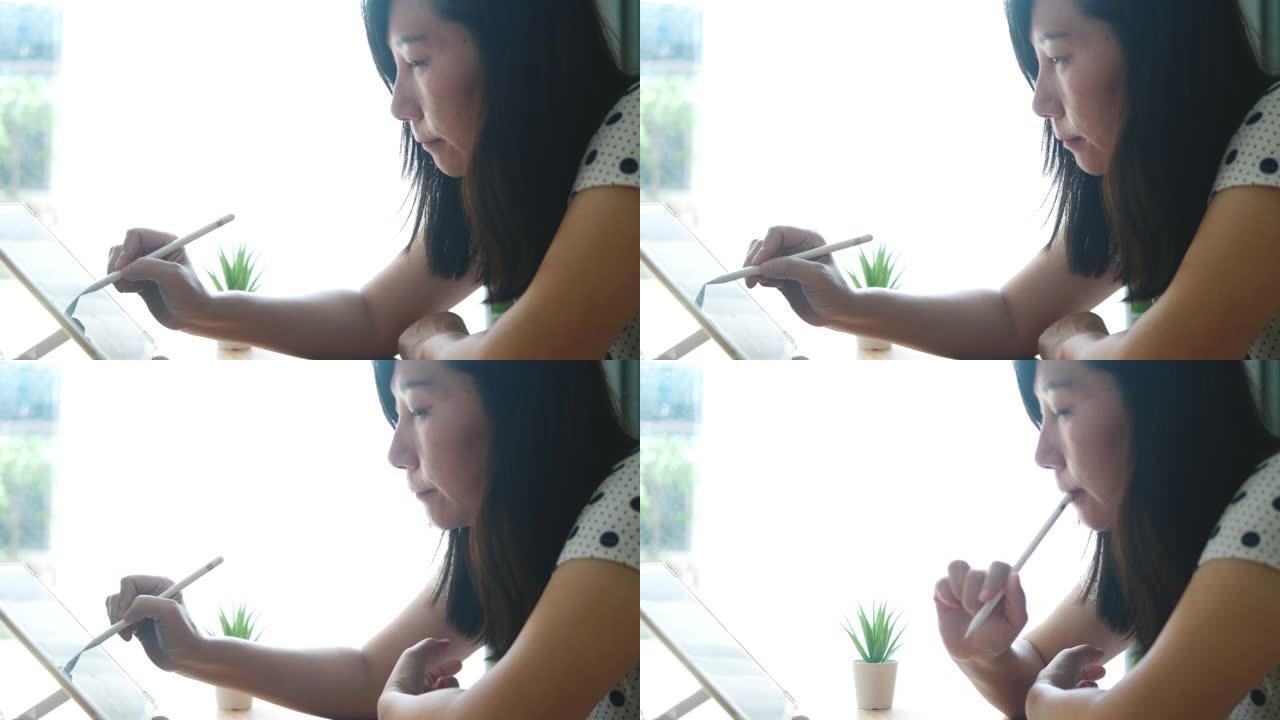 亚洲妇女使用数字平板电脑在新型冠状病毒肺炎期间在家工作。