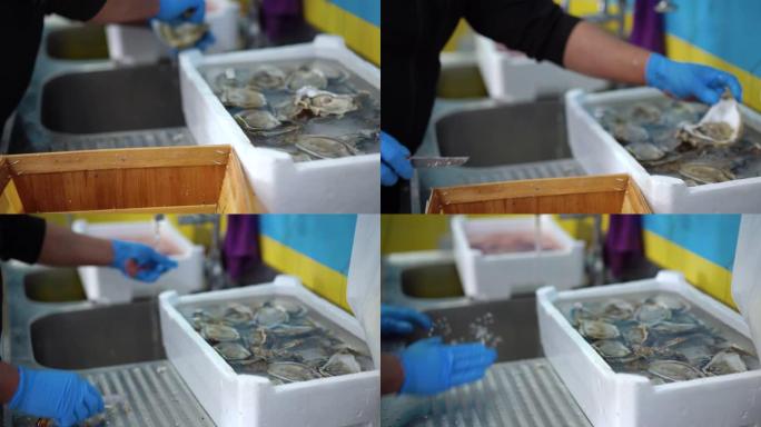 戴着手套的专业渔民在鱼市场柜台上剥新鲜牡蛎，并准备出售。市场柜台上新鲜昂贵的美味。Sellerman