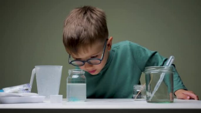 戴眼镜的男孩在室内用移液管和液体进行化学实验。学习，兴趣学习。另类教育。研究背景。成功学习的个人素质