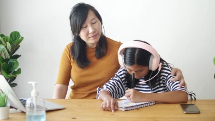 亚洲男孩和女孩使用笔记本电脑和数字平板电脑在新型冠状病毒肺炎期间在家上学。