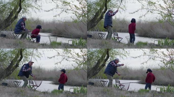 钓鱼时，爷爷和小男孩在乡间的芦苇和树木间休息时，用鱼竿在河里钓小鱼