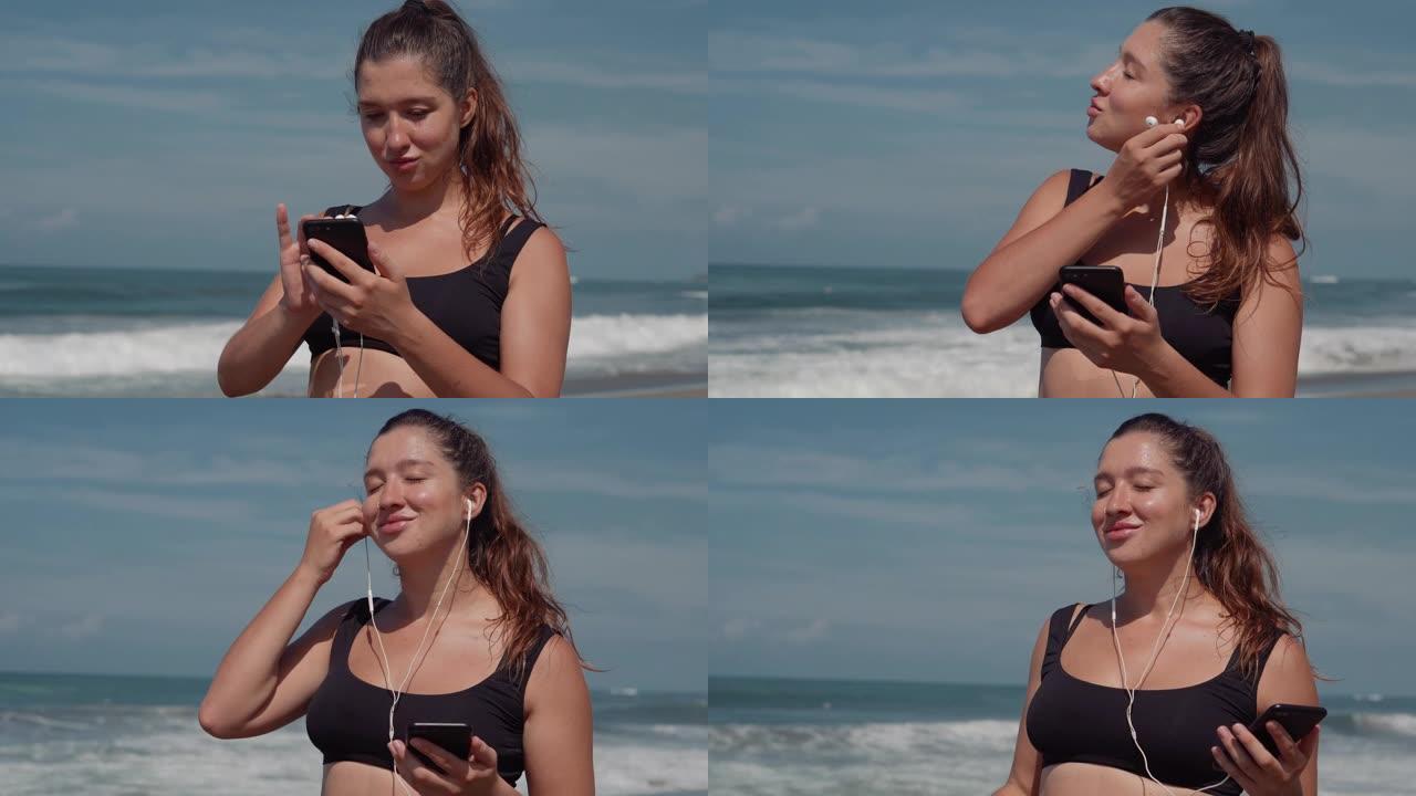 女人正在海边用智能手机和耳机听音乐