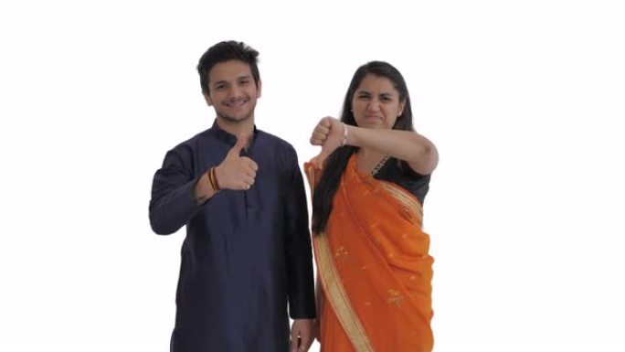 印度夫妇表现出相反的情感。微笑的男人竖起大拇指。皱着眉头的女人展示着拇指。孤立在白色背景上