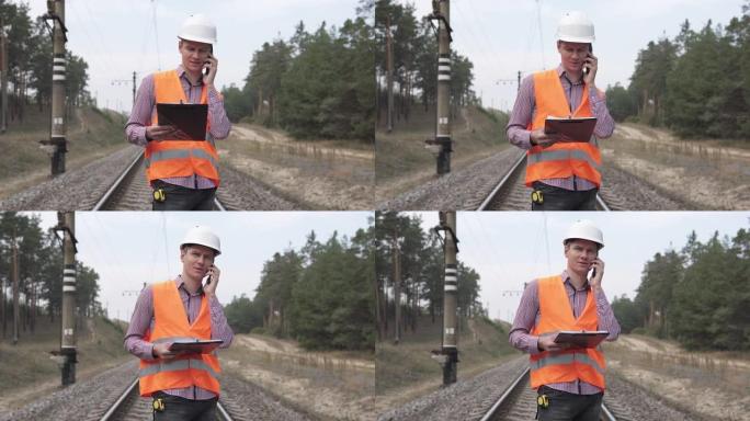 一名铁路工程师站在铁轨上，通过电话与上级进行了交谈。