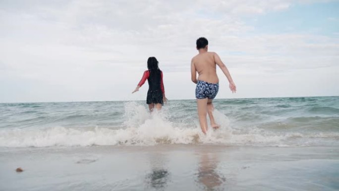 度假期间，快乐的亚洲儿童在华欣海滩跑步。