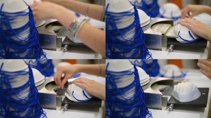 这个女孩在一家工厂工作，生产带有纳米纤维的医用口罩，并在机器上使用超声波焊接环。冠状病毒和新型冠状病