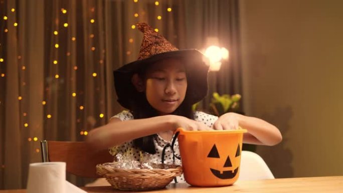 戴着魔杖的女巫帽子的亚洲女孩在晚上在家玩万圣节概念。