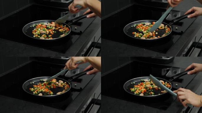 智能现代厨房感应锅上的油炸蔬菜。烹饪过程。女性手在锅上准备煮菜。健康食品