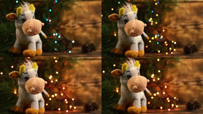 毛绒玩具公牛，牛，在黑暗板上云杉树枝上的节日花环的背景下
