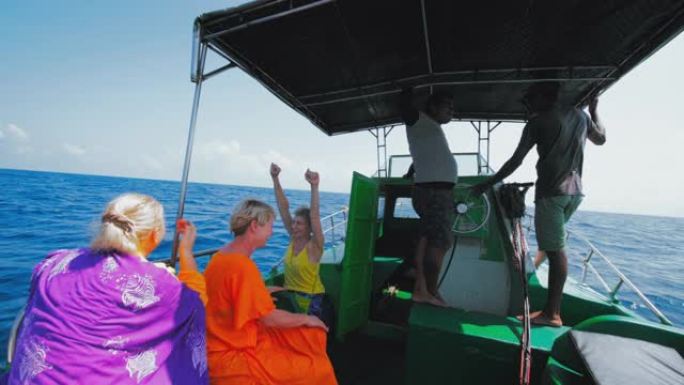 在斯里兰卡海岸的印度洋深海捕鱼之旅中，欧洲妇女的游客在帐篷下的阴凉处休息，并与当地向导和渔船上的船长