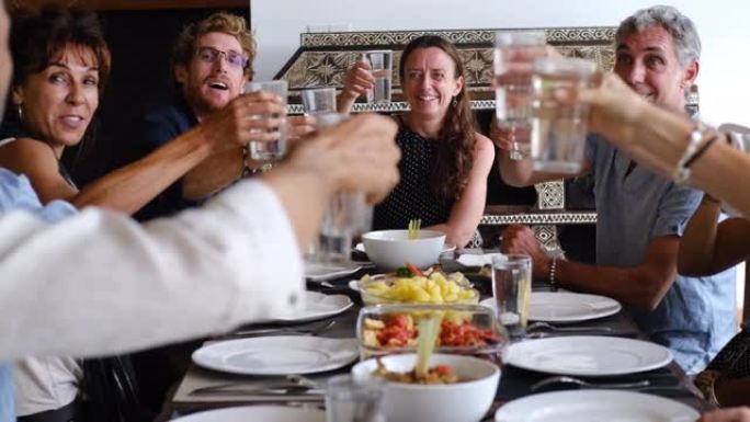 多元化的多民族朋友群体，他们戴着眼镜敬酒，在户外咖啡馆或家里用餐。休闲、饮食、人与假日概念