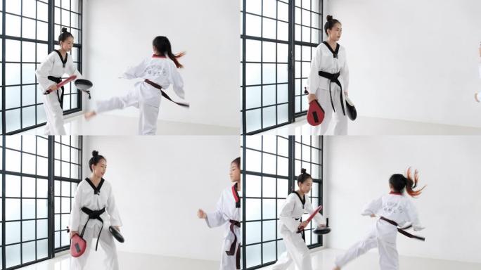 跆拳道女教练通过使用一些工具向学生传授技术，以在健身房进行前踢。