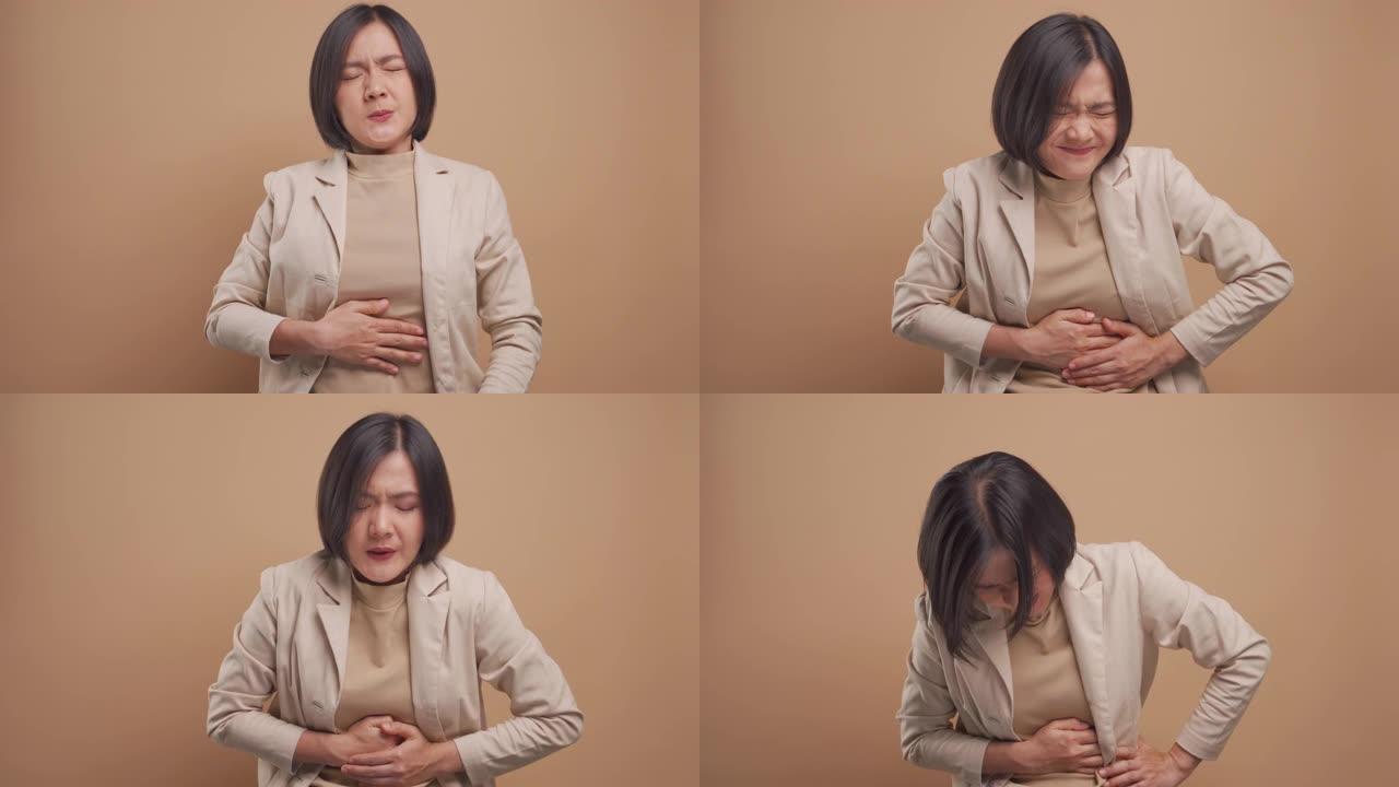 亚洲女商人因胃痛而生病，站在米色背景上与世隔绝。4k视频