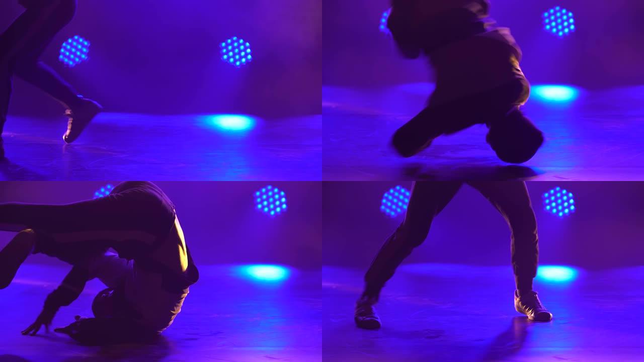 年轻的霹雳舞舞者在黑暗的工作室里在地板上旋转。聚光灯下一个动态跳舞的人的剪影。特写