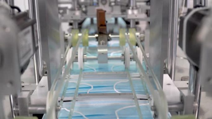 工业工厂用自动机械生产线生产医用口罩的过程。冠状病毒大流行或新型冠状病毒肺炎爆发期间的短缺