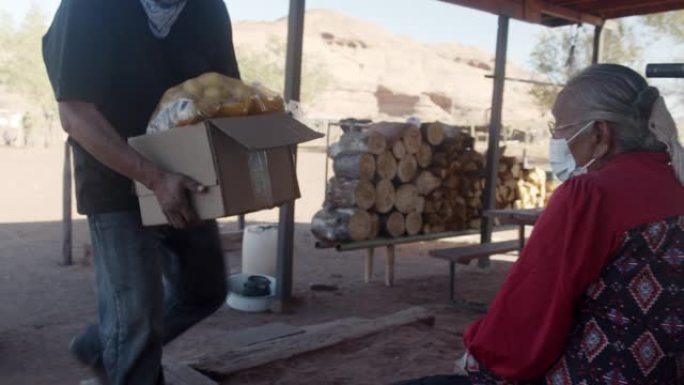 居住在纪念碑谷纳瓦霍人保留地的纳瓦霍人在新型冠状病毒肺炎期间向一名纳瓦霍人老年妇女运送一盒食物
