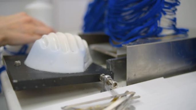 一名妇女在一家工厂工作，生产带有纳米纤维的医用口罩，并在机器上使用超声波焊接环。冠状病毒和新型冠状病