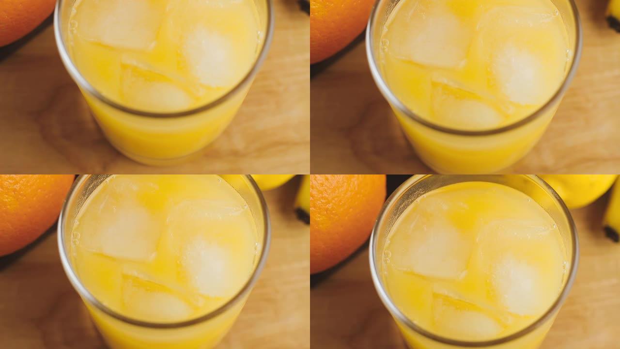 全杯有机橙汁和冰块放在木制桌子上，极端特写