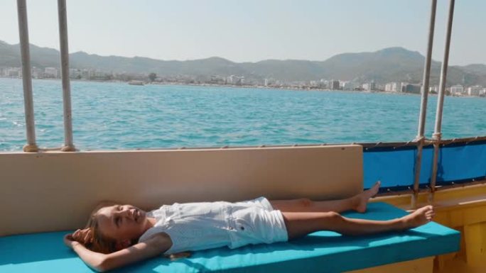 旅游女孩在海上漫步的浮动游艇上放松。年轻女孩躺在帆船上夏季海上巡航。乘坐海船旅行的少女。