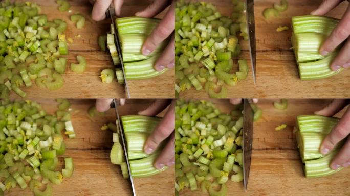 在木制切割表面的餐厅厨房里用刀切碎芹菜。厨师切芹菜在厨房做饭。手在砧木板上用刀切片芹菜背景。慢动作。