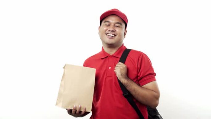 微笑的年轻亚洲送货员穿着红色制服，拿着包裹纸袋站在孤立的白色背景上。4k分辨率。