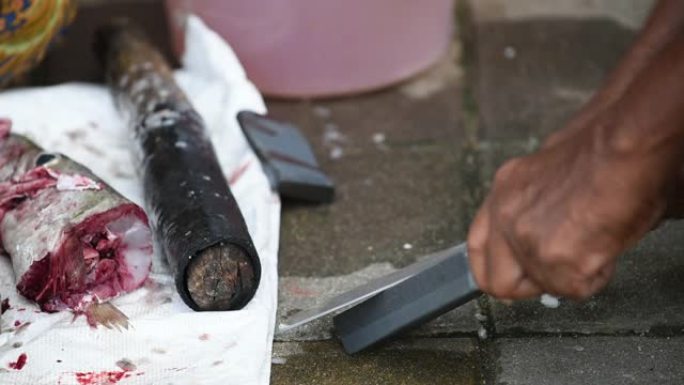 一名男子在街头当地市场削刀割鱼