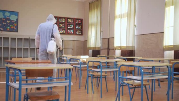 环卫工人在上学的第一周使用抗菌剂对新生的教室和桌子进行消毒