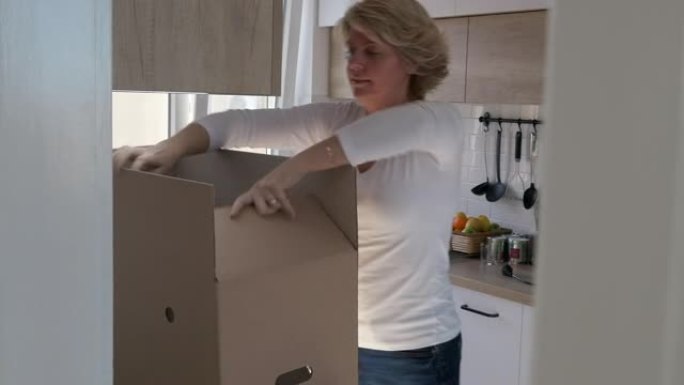 一名妇女正在制作一种新的纸板箱，她将纸板箱的边折起来，然后用胶带封好