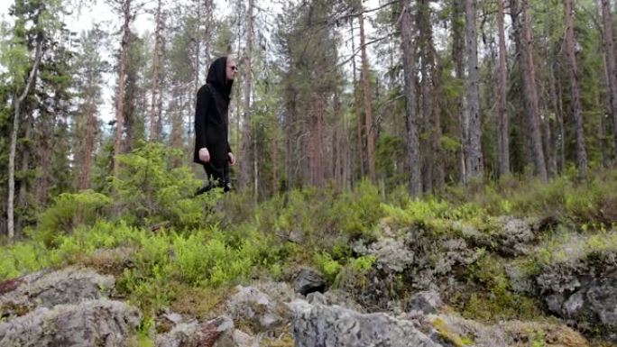 穿着黑色衣服的人独自走在深深的岩石森林里。旅行、健康积极的生活方式、冒险、户外娱乐