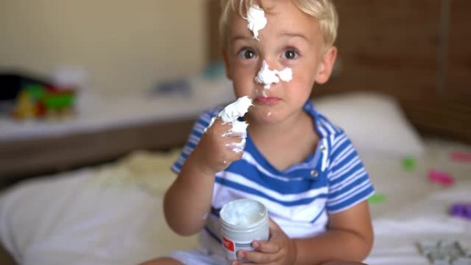 可爱的小男孩在鼻子上涂上面霜。