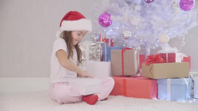 好奇的小女孩晚上不被注意到圣诞树，打开一个礼物盒子，魔术灯从里面照亮，孩子确定没人看到她，关上盒子并