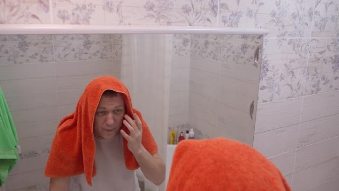早晨的一个男人，用毛巾蒙住头，洗完澡照照镜子，酗酒