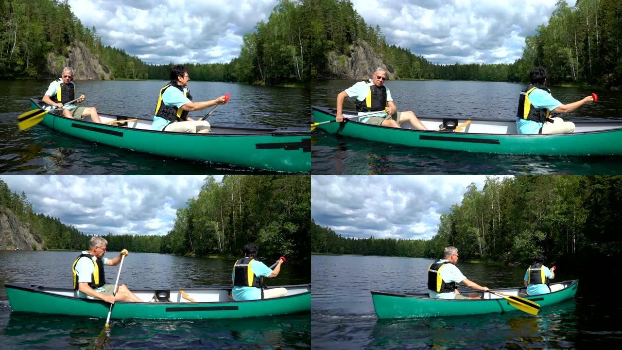 成熟的夫妇在芬兰的森林湖上划独木舟。