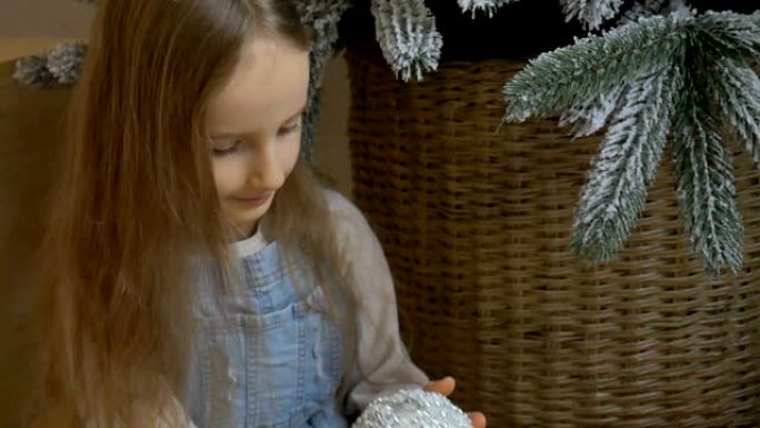 小女孩正在用大银小玩意装饰圣诞树。可爱的金发女孩子正在为圣诞节庆祝做准备。