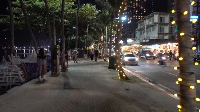 芭堤雅的步行街沿着海滩晚上。人，车，灯，棕榈树，游客，海，海滩。