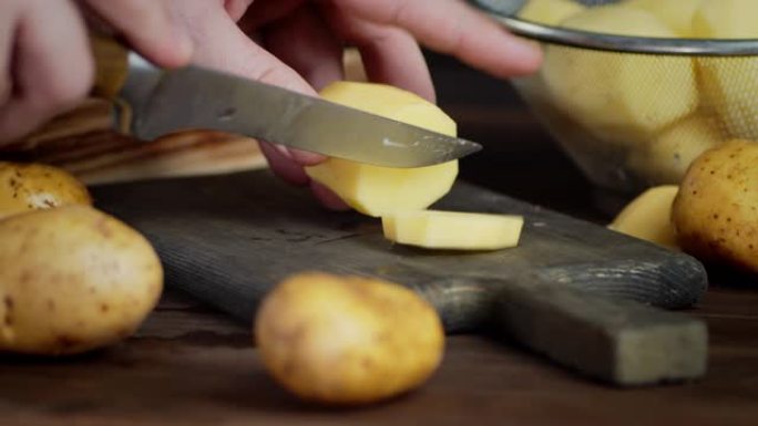 男性用刀将新鲜土豆切成圆片。