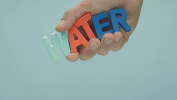 手将彩色字母 “水” 的铭文放入水中。