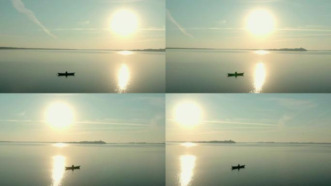 日出时船上渔民的空中无人机视图，早晨钓鱼，黎明时在平静的湖上游泳