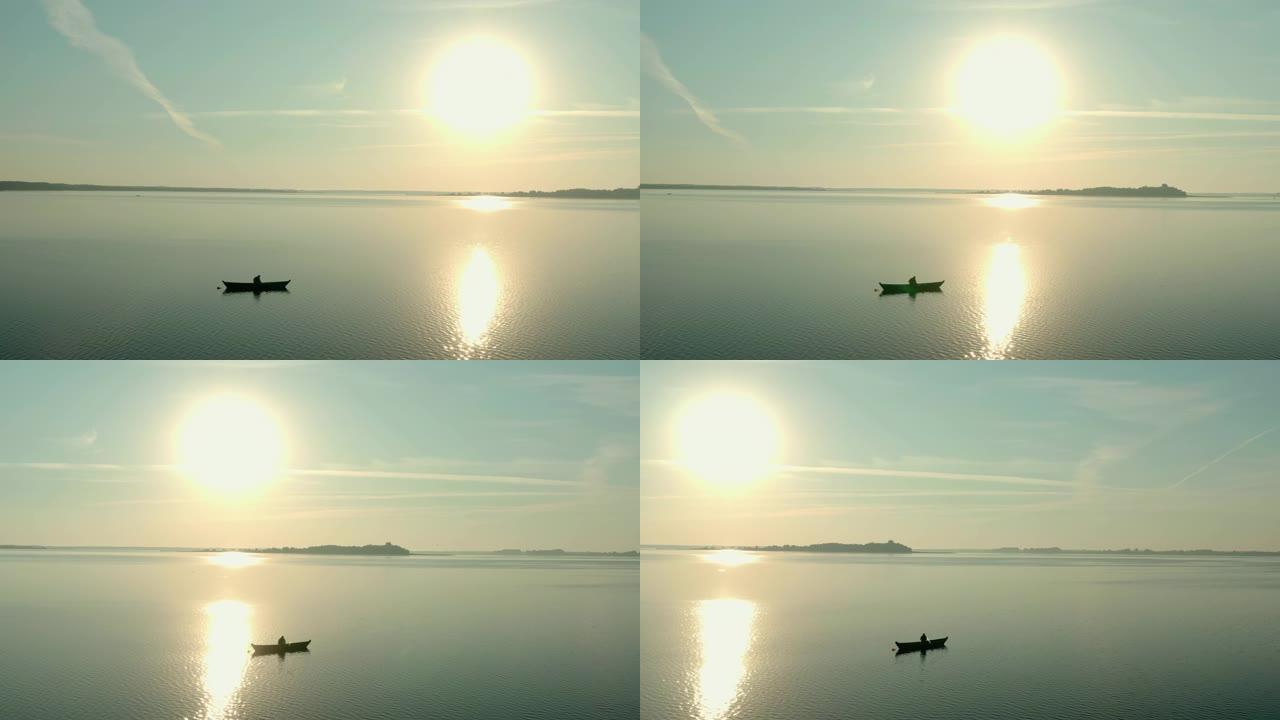 日出时船上渔民的空中无人机视图，早晨钓鱼，黎明时在平静的湖上游泳