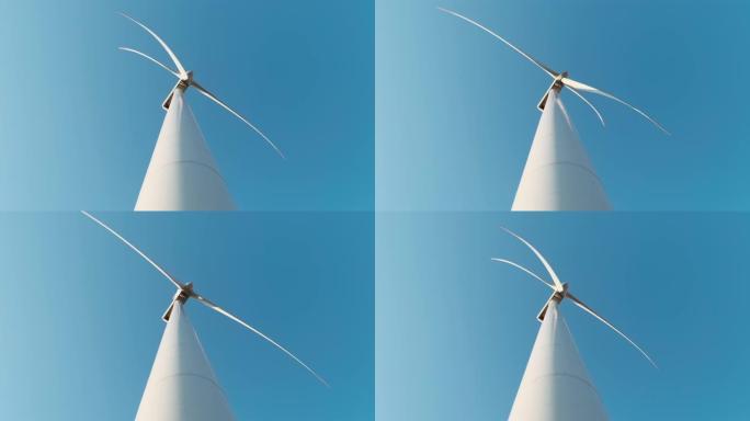 在阳光明媚的夏日，野外慢动作中，大型风力涡轮机的叶片抵御蓝天。从下往上看。替代能源。风电场。生态能源