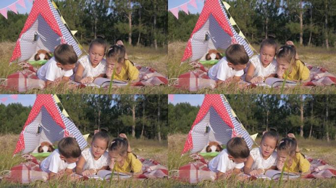 孩子们在大自然中休息，可爱的小朋友们喜欢在森林里休息，在暑假期间躺在野餐覆盖物上阅读有趣的书