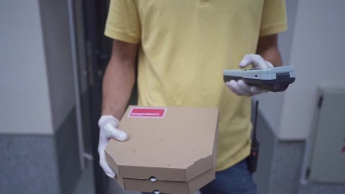 披萨送货员拿着两个披萨盒，在条形码阅读器上输入信息