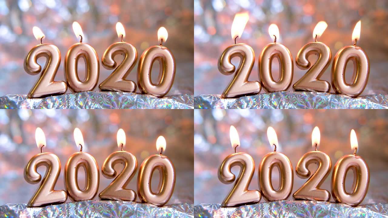 文本2020金色蜡烛燃烧。模糊的闪光银色背景。圣诞快乐，新年快乐。选择性聚焦。创意现场贺卡。4k镜头